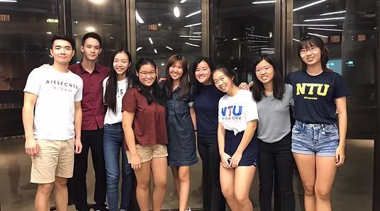 Nine AIESEC NTU members standing together, several wearing NTU shirts